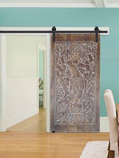 a wooden door with carvings on it in a dining room next to a table and chairs