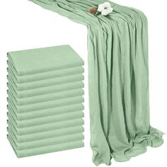 a stack of green towels next to a pile of folded towels on a white background