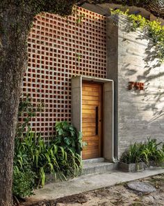 an entrance to a house made out of bricks and concrete with plants growing on the side