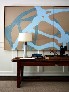 a table with a lamp and some books on top of it next to a painting