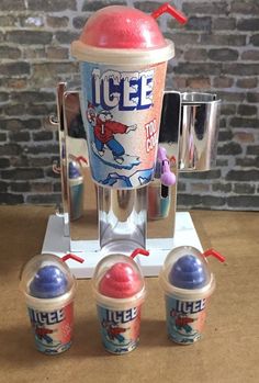 an ice cream dispenser with three cups in front of it on a table