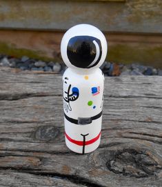 a small white and black toy sitting on top of a wooden table next to rocks