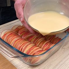 a person pouring liquid into a bowl filled with sliced apples