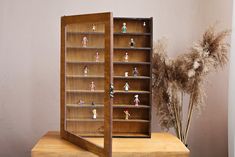 a display case with figurines in it on a table next to dried flowers