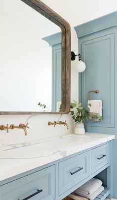 a bathroom with blue cabinets and a large mirror above the sink is shown in this image