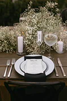 a table set with white flowers and silverware for an elegant wedding reception in the garden