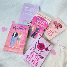 four books are laying on a bed with hearts around them and one has a pink rose in the middle