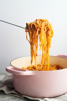 someone is eating spaghetti in a pink bowl