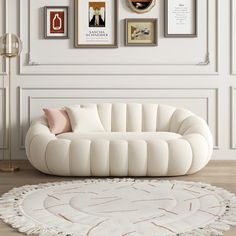 a living room with white furniture and pictures on the wall above it, along with a round rug