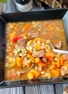 a bowl of soup with meat, carrots and corn