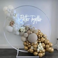 a white and gold balloon arch with balloons in it that say better together on the wall