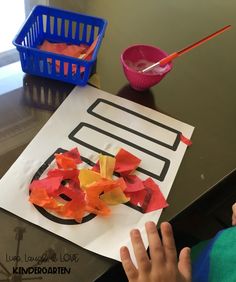 a child is making a paper plate craft with tissue paper and construction paper on the table