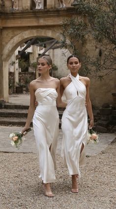 two women in white dresses are walking together