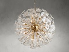 a clear glass ball light hanging from a ceiling fixture on a gray background with gold accents