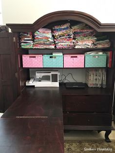 a sewing machine sitting on top of a wooden desk next to a shelf filled with fabric