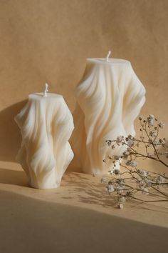 two white candles sitting next to each other on a table