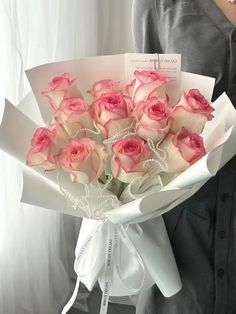 a woman holding a bouquet of pink roses