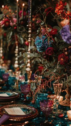 a table topped with lots of different types of plates and cups filled with flowers next to candles