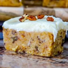 a piece of carrot cake with white frosting and pecans