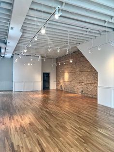 an empty room with hard wood floors and exposed ceiling lights on either side of the wall