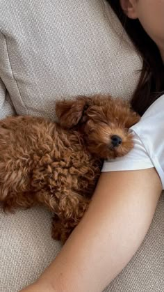 a woman laying on a couch holding a brown dog with it's eyes closed