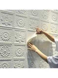 a man is working on a wall with white paint and decorative plaster tiles in the shape of flowers