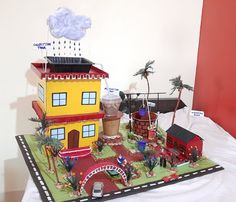 a cake made to look like a house with cars and buildings on the front yard