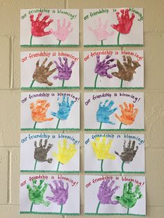 four handprints with different colors and words on them hanging from a brick wall