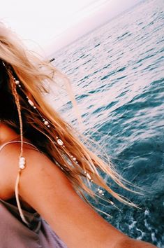 a woman riding on the back of a boat in the middle of the ocean with her hair blowing