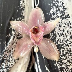 a pink flower with white spots hanging from a chain