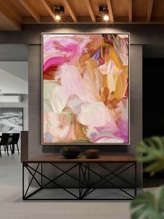 an abstract painting hangs on the wall above a table