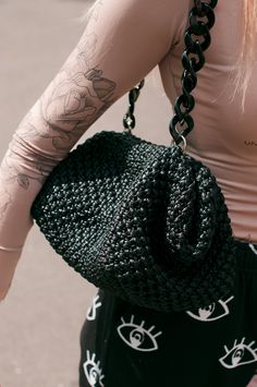 a woman carrying a black crocheted purse on her back with tattoos and piercings