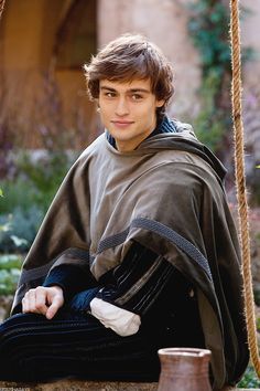 a man sitting on the ground wearing a cape