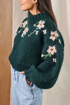 a woman wearing a green sweater with flowers on it