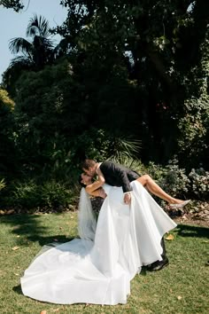 a bride and groom kissing in the grass