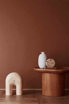 a white vase sitting on top of a wooden table next to an elephant shaped object