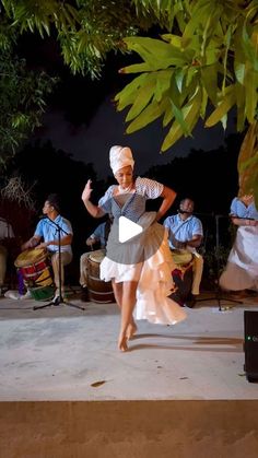 a woman dancing on stage with other people in the background