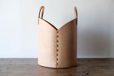 a brown leather basket sitting on top of a wooden table