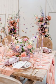 the table is set with pink and purple flowers