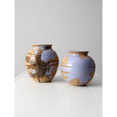 two vases sitting side by side on a white counter top, one with an abstract design