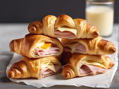 ham and cheese croissants stacked on top of each other with a glass of milk in the background