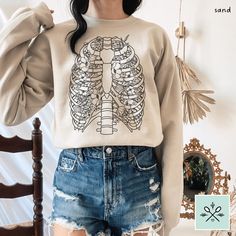 🌟 Want 10% off this item?? Join our email list here! https://www.alura.io/subscribe?=SpoonieSisterShop  Floral ribcage sweatshirt, featuring delicate flowers paired with a cool vintage-inspired anatomy design! Perfect for chronic illness warriors, physical therapists, med students, and overall anatomy lovers! Comfy, unisex relaxed fit sweater that's flattering for everyone. DETAILS: * Made to order * Unisex adult sizing (size chart in photos) * 50% Cotton, 50% Polyester * Machine wash cold with like colors, hand dry or tumble dry low 🌿 Cute coordinating Floral Ribs Anatomy T-Shirt available here: https://spooniesistershop.etsy.com/listing/1757002107 If you have any questions regarding this listing, please hit the "Ask a Question" button next to the price, and I will get back to you withi Ribcage Sweatshirt, Ribs Anatomy, Slipping Rib Syndrome, Floral Ribcage, Skeleton Ribs, Anatomy Design, Spoon Theory, Med Student, Delicate Flowers