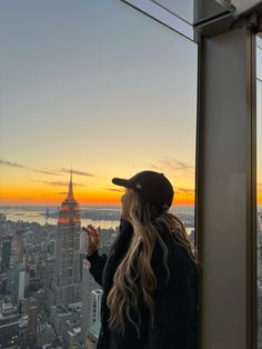 a woman standing on top of a tall building looking out at the cityscape