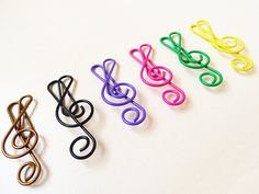 four different colored paper clips sitting on top of a white table next to each other