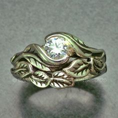 a close up of a ring with a diamond in the center and leaves on it