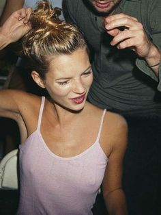 a woman getting her hair styled by a man at a party with other people in the background