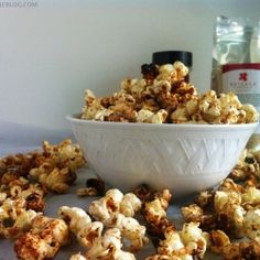 a white bowl filled with caramel popcorn on top of a table next to bottles