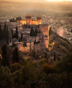 an old castle sits on top of a hill in the middle of town at sunset