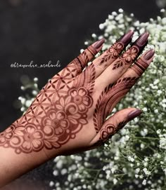 a woman's hand with henna on it and white flowers in the background