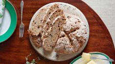 a loaf of bread sitting on top of a wooden table next to plates and silverware